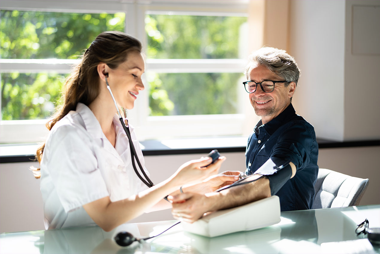 Ärztin misst während des Gesundheits-Check-ups bei einem Mann Blutdruck,