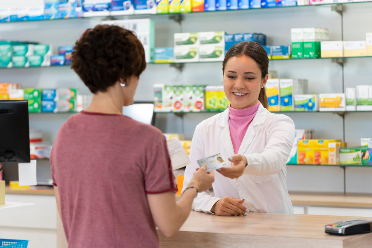 Frau übergibt in Apotheke die Gesundheitskarte an die Apothekerin.