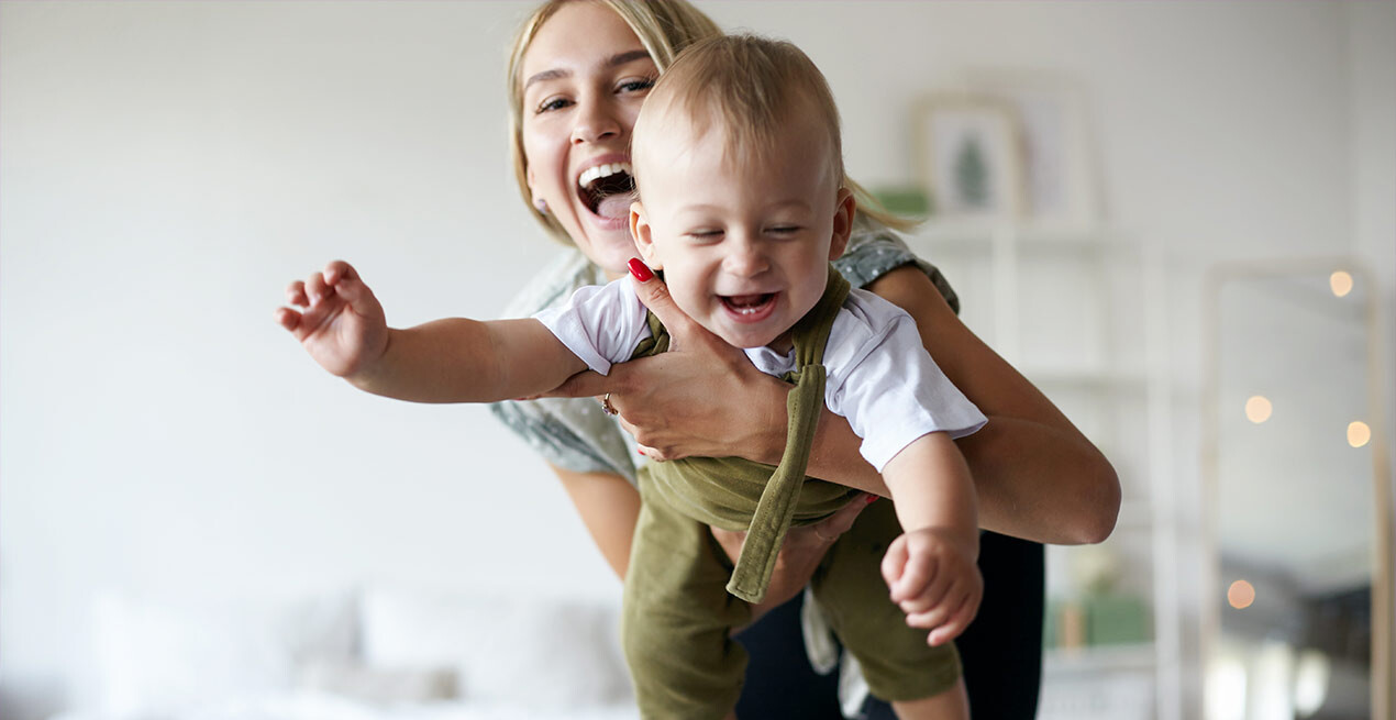 Lachende Mutter mit ihrem Baby im Arm