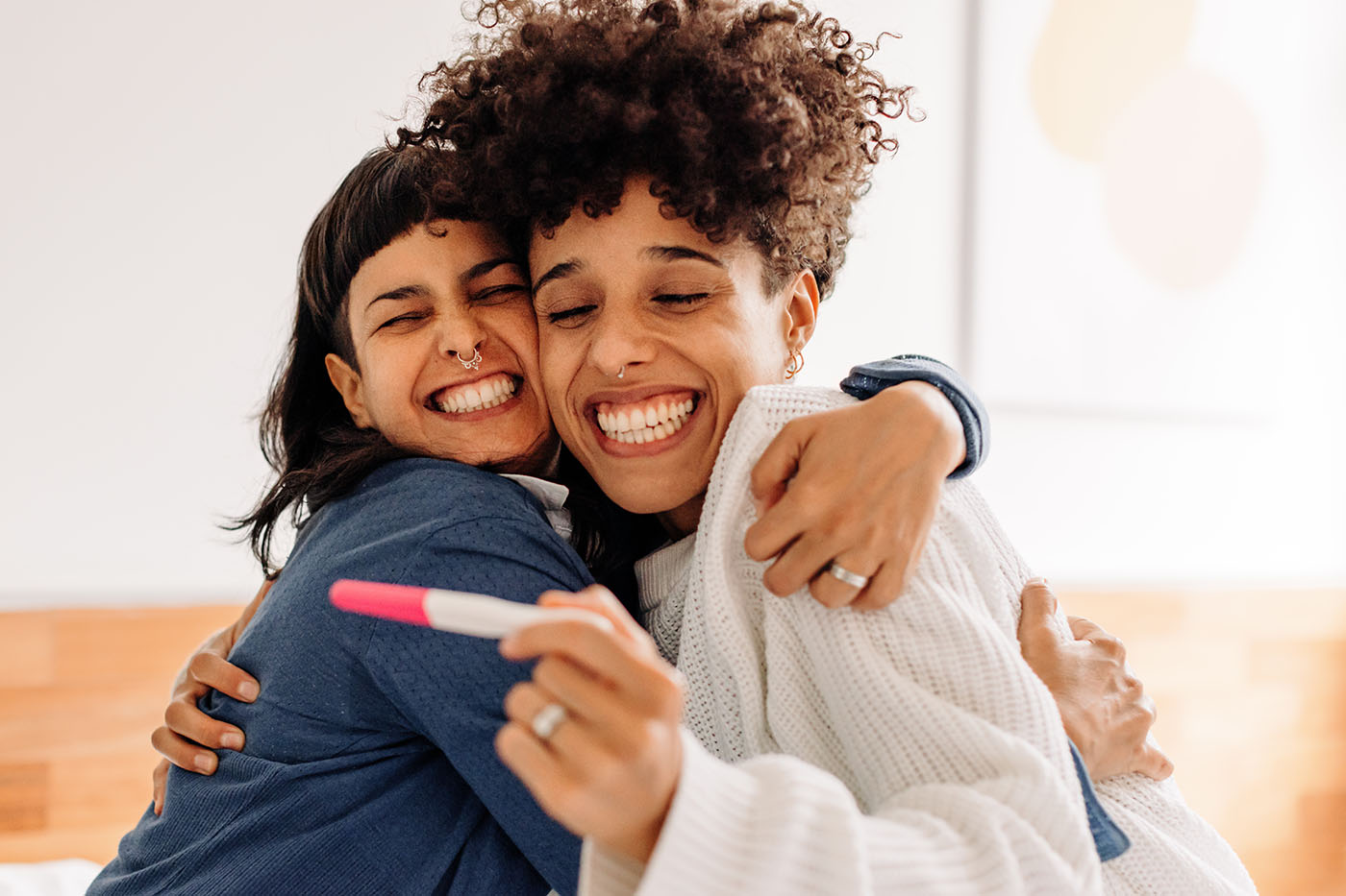 Zwei Frauen, die sich umarmen und über den positiven Schwangerschaftstest freuen