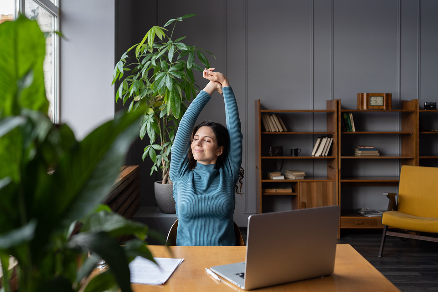 Frau, die am Schreibtisch sitzt und sich streckt