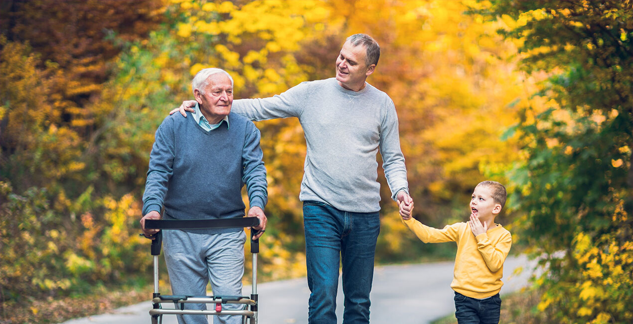 Ein Vater geht mit seinem Sohn und seinem altem Vater im Park spazieren