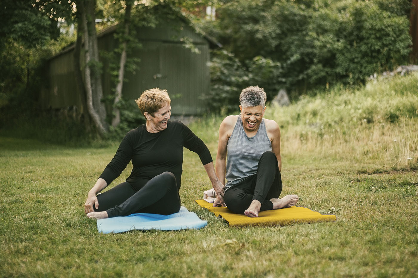 Zwei Frauen, die im Grünen Übungen auf einer Yogamatte machen