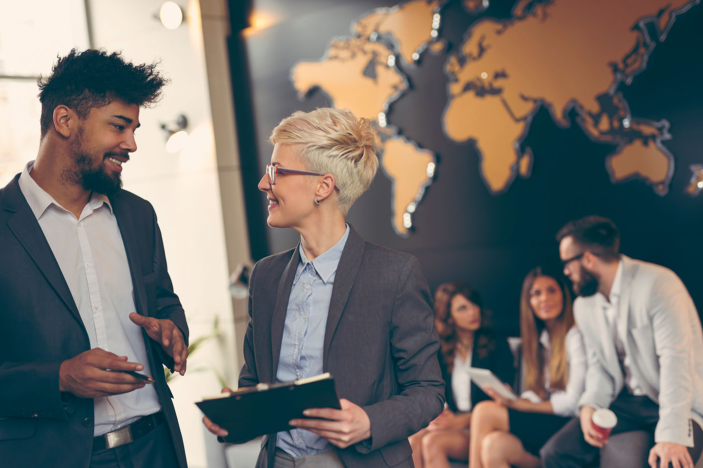 Internationale Beschäftigte im Büro, die sich vor einer Weltkarte unterhalten