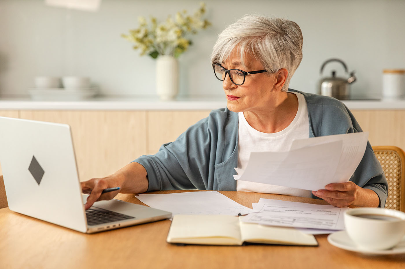 Frau mit Dokumenten und Anträgen am Laptop