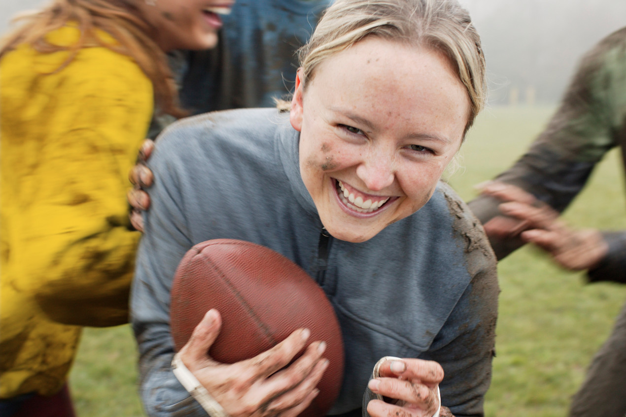 Junge Frau verdreckt beim Rugby-Spielen mit Freunden.