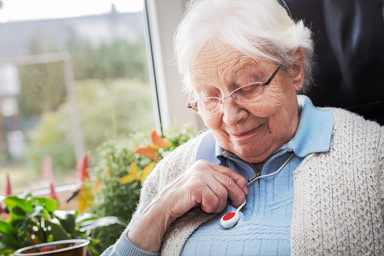 Eine Seniorin mit einem Notrufgerät