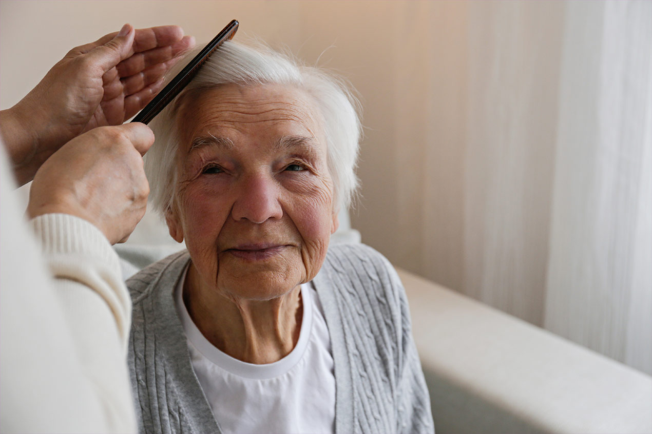 Seniorin, der die Haare gekämmt werden