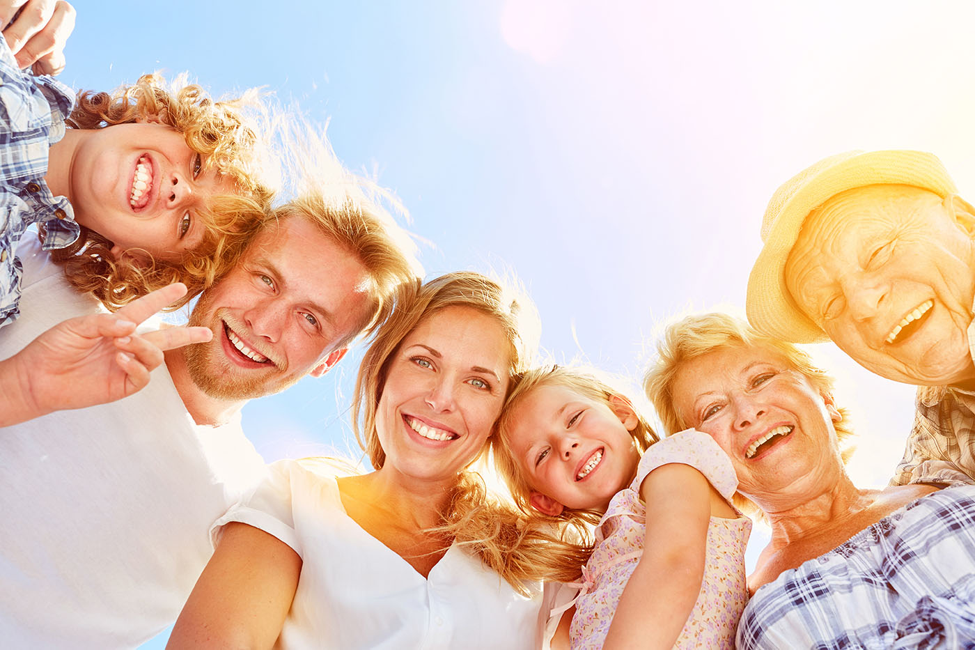 Gemeinschaft, Familie mit Kindern und älteren Menschenn schaut hinab in die Kamera, blauer Himmel