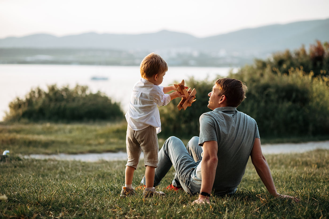 Vater, der mit seinem Sohn in der Natur mit einem Spielzeugflieger spielt