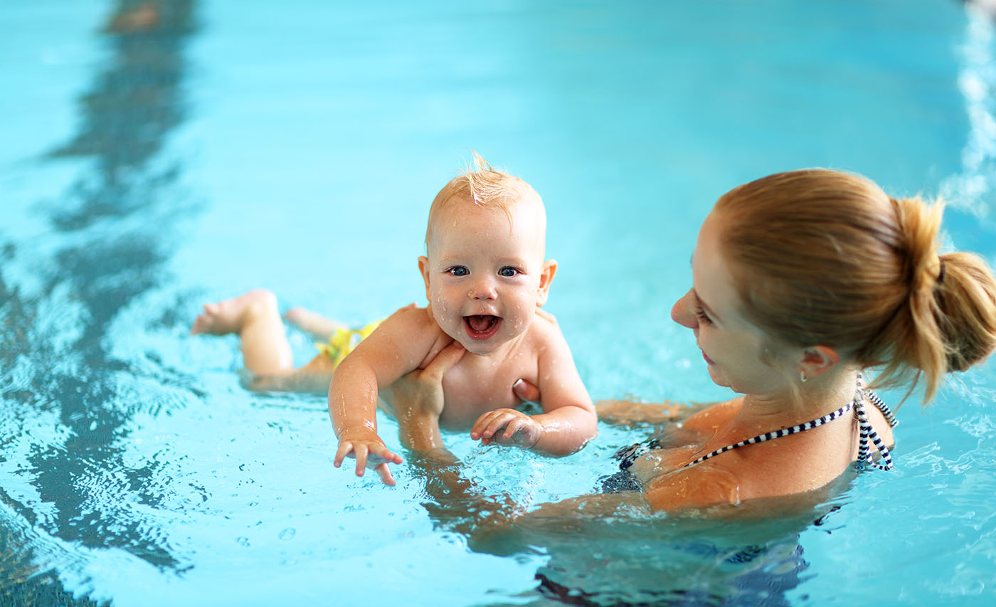 Frau mit ihrem Kind im Wasser beim Babyschwimmen