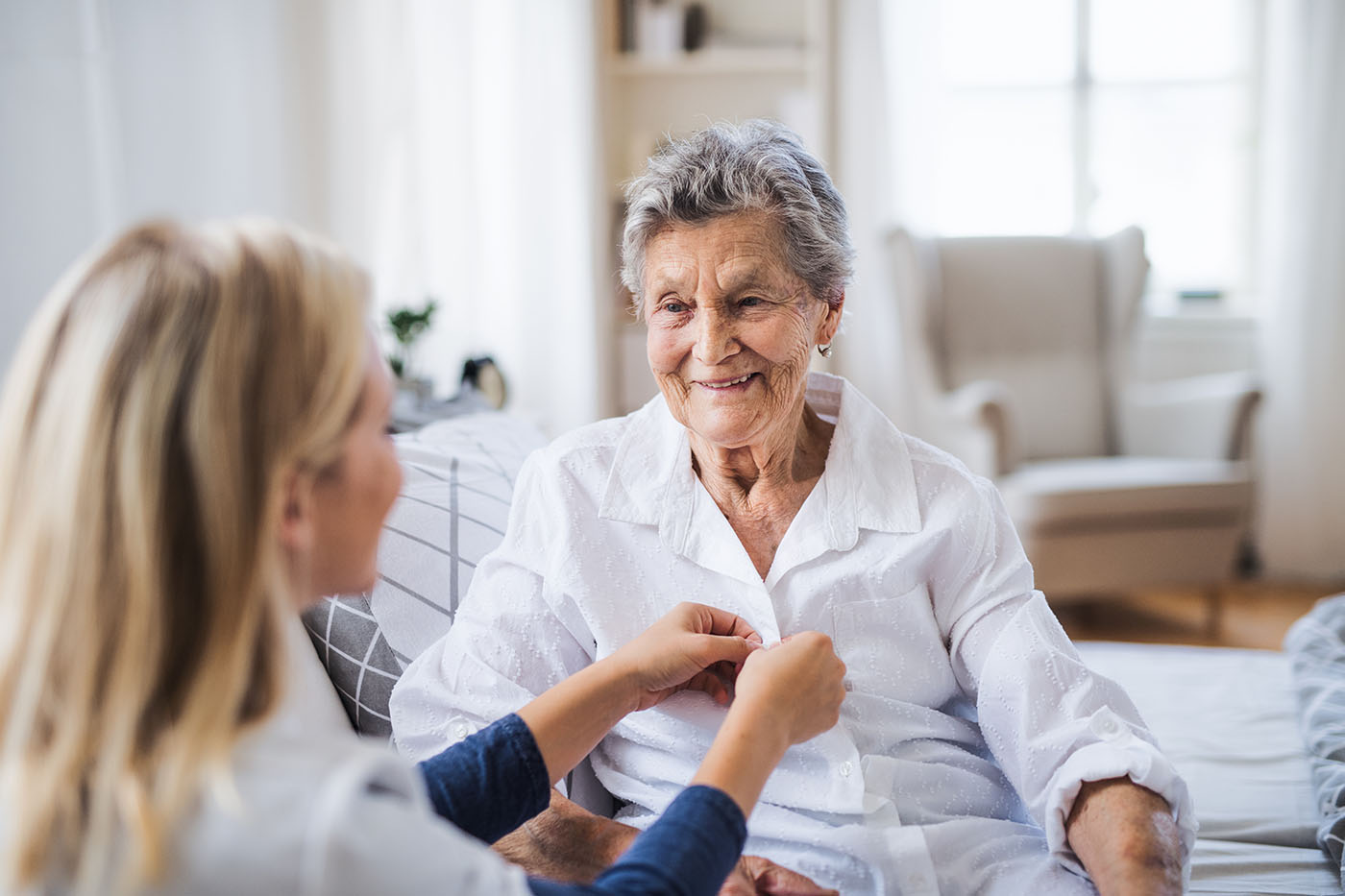 Eine Beschäftigte des Pflegedienstes versorgt Seniorin zu Hause