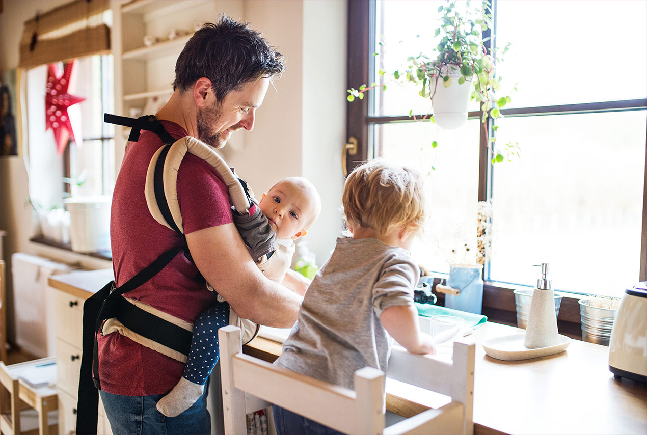 Vater während der Elternzeit mit seinem 2 kleinen Kindern in der Küche