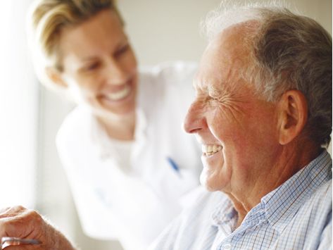 Pflegekraft und alter Mann lachen gemeinsam