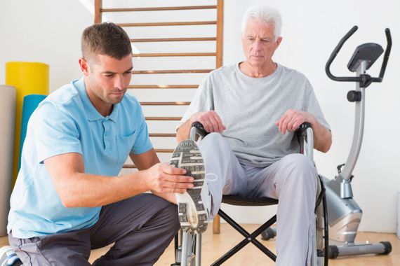 Physiotherapeut dehnt Fuß und Bein seines Patienten